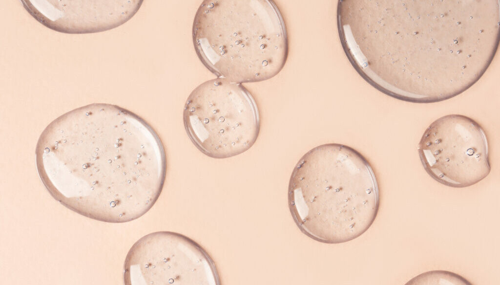 Drops and smears of cosmetics. Drops of liquid transparent gel with bubbles on a brown background.