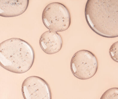 Drops and smears of cosmetics. Drops of liquid transparent gel with bubbles on a brown background.